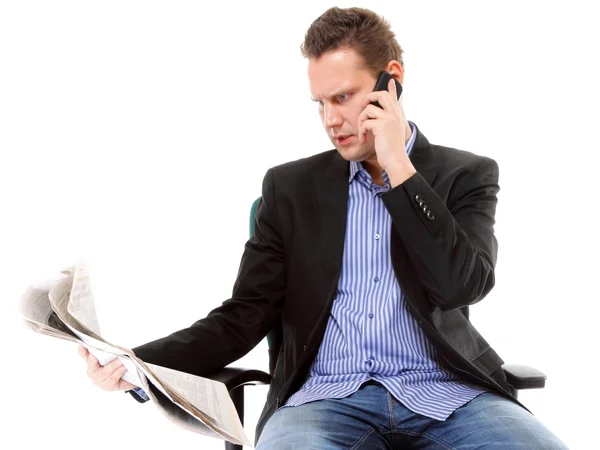Jovem empresário lê jornal enquanto telefona — Fotografia de Stock