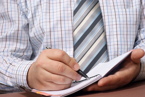 Närbild av en affärsman hand med en penna som skriver något. — Stockfoto