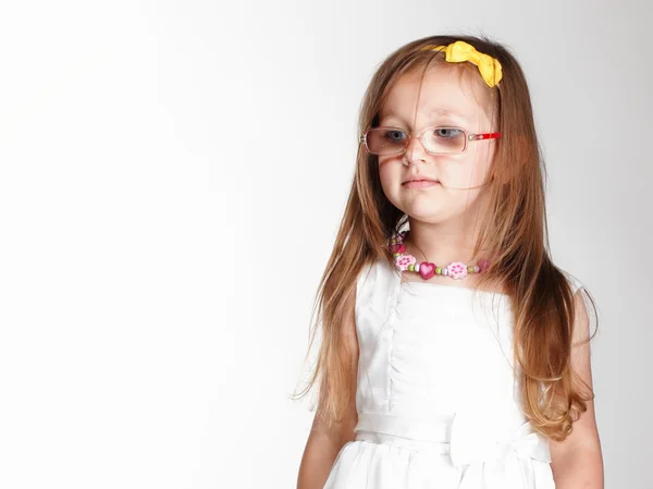 Schattig klein meisje in witte jurk glazen — Stockfoto