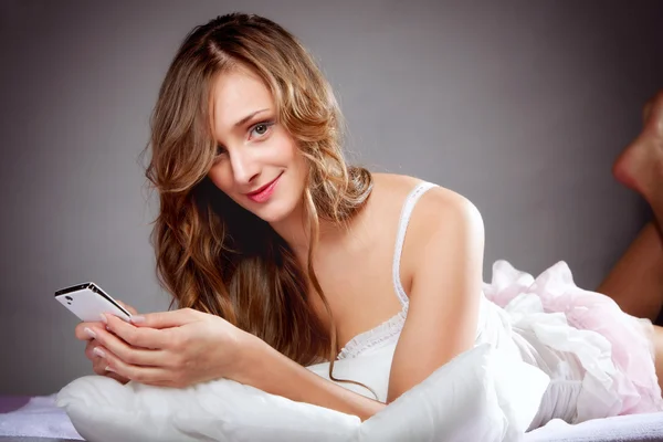 Mujer acostada en la cama con teléfono —  Fotos de Stock