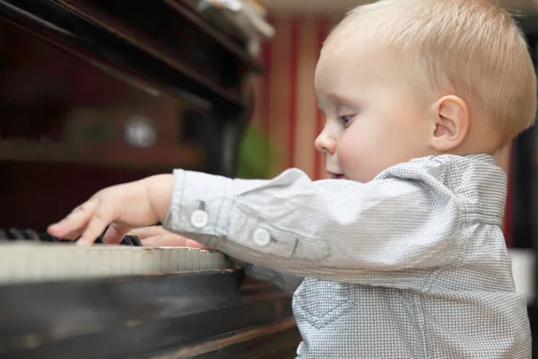 Menino tocando piano interior — Fotografia de Stock