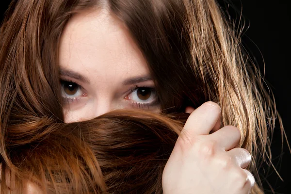 Primeros planos mujer cubre la cara por largos pelos marrones —  Fotos de Stock