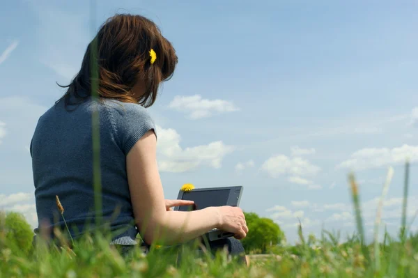 Frau tippt draußen auf einer Wiese auf einem Laptop — Stockfoto