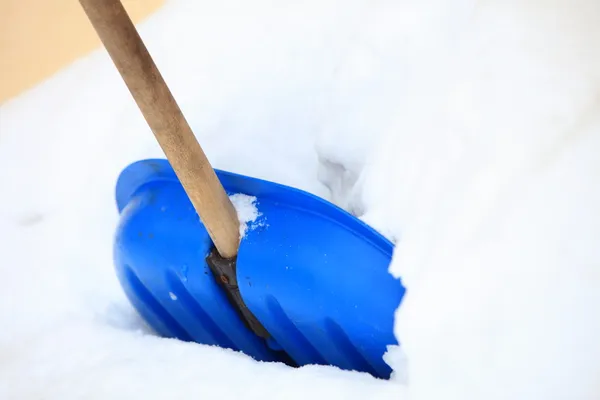 Голубая снежная лопата, стоящая в глубоком снегу — стоковое фото