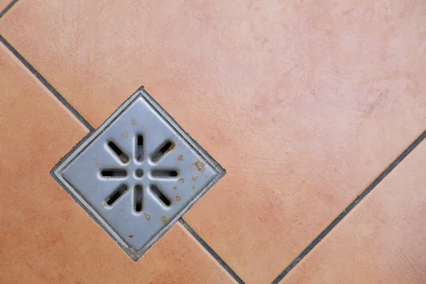 Sewer grate drain water on floor in bathroom — Stock Image Sewer grate drain water on floor in bathroom Royalty Free Stock Images