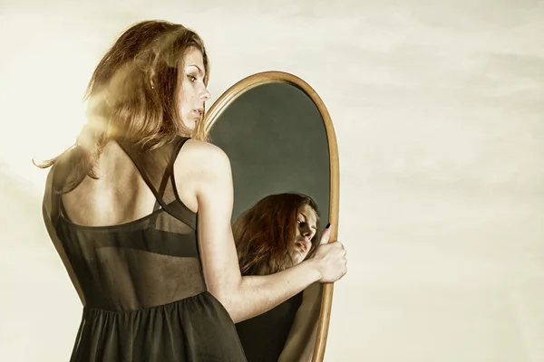 Thoughtful woman looks at the reflection in mirror — Stock Photo, Image