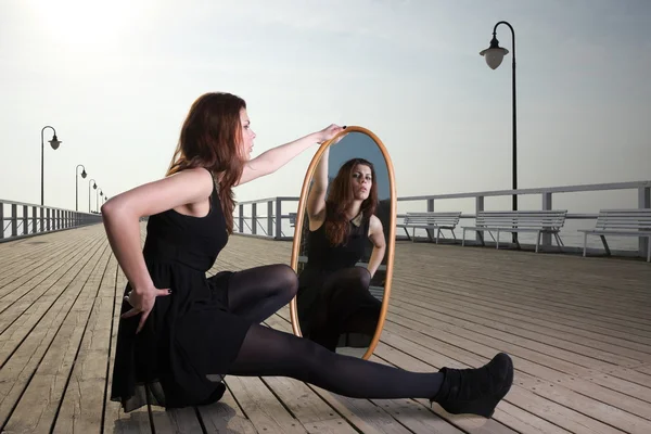 Doordachte vrouw kijkt naar de reflectie in de spiegel — Stockfoto