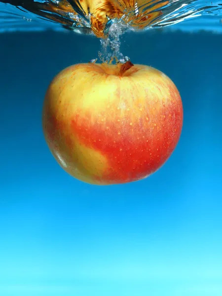 Κίτρινο μήλο στο νερό πιτσιλίζει πάνω από το μπλε — Φωτογραφία Αρχείου