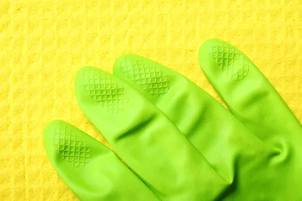 Yellow sponge and green rubber glove — Stock Photo, Image