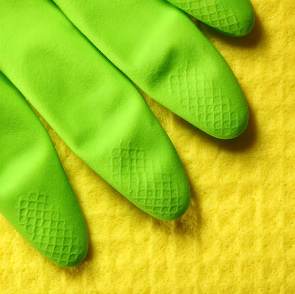 Yellow sponge and green rubber glove — Stock Photo, Image