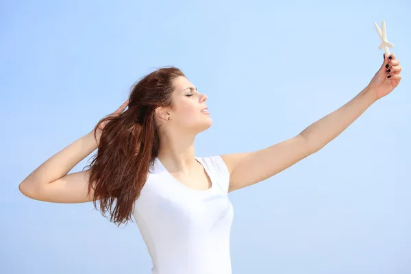 Young woman on seacoast with shell in hand — Stock Photo, Image