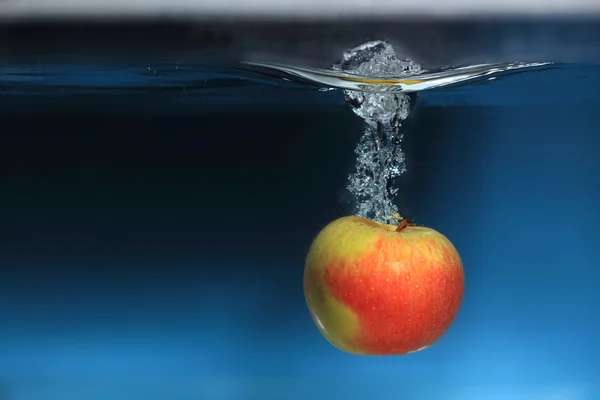 Mela nella spruzzata d'acqua su sfondo blu — Foto Stock