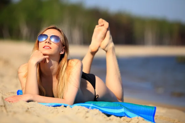 Lachende mooie vrouw zonnebaden op een strand — Stockfoto