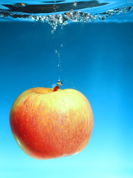 Pomme jaune dans l'eau éclabousser sur le bleu — Photo