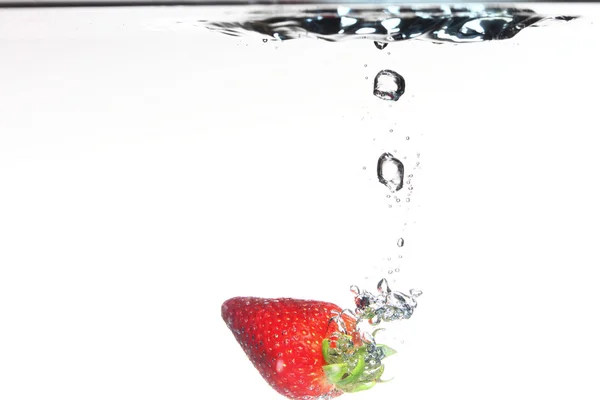 Aardbeien in het water spatten over wit — Stockfoto