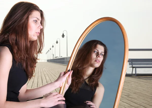 Tankeväckande kvinnan ser på reflektion i spegeln — Stockfoto