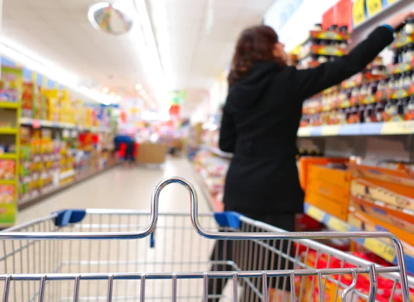 Frau im Supermarkt mit Einkaufswagen Stockbild