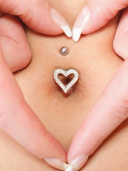 Ręce serce symbol wokół piercing pępka — Zdjęcie stockowe