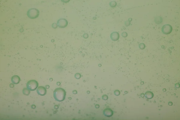 Tekuté mýdlové bubliny zelené pozadí — Stock fotografie