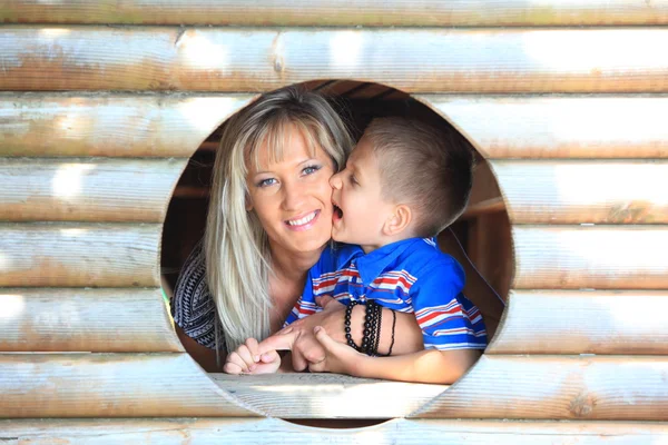 Mãe e filho espreitam através do buraco no playground — Fotografia de Stock