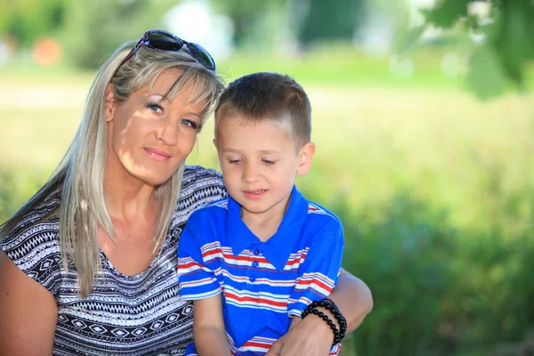 Felice famiglia madre e figlio sulla panchina nel parco — Foto Stock