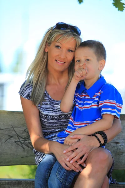 Feliz familia madre e hijo en el banco en el parque — Foto de Stock