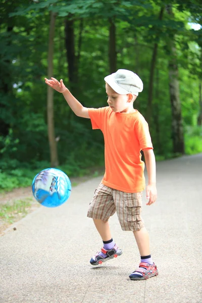 Garçon jouer avec la balle dans le parc à l'extérieur — Photo