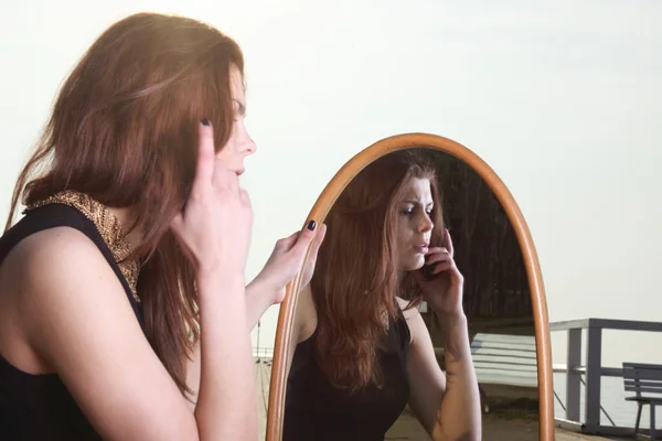 Doordachte vrouw kijkt naar de reflectie in de spiegel — Stockfoto