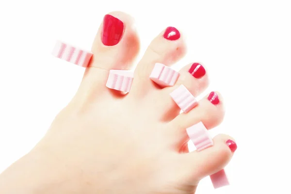 Pedicure del piede applicando unghie rosse su bianco — Foto Stock