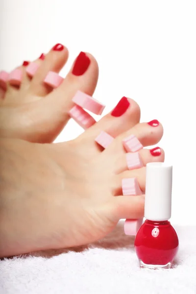 Pedicure del piede applicando unghie rosse su bianco — Foto Stock