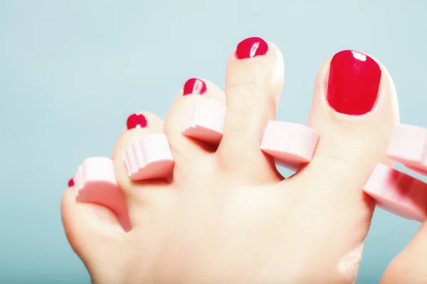 Pedicure del piede applicando unghie rosse su blu — Foto Stock