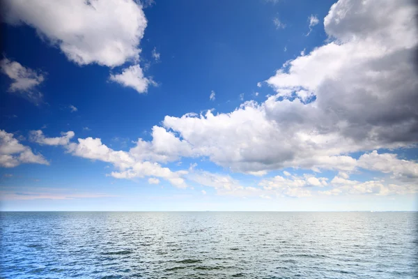 Cloudy blue sky above a surface of the sea — Stock Photo, Image