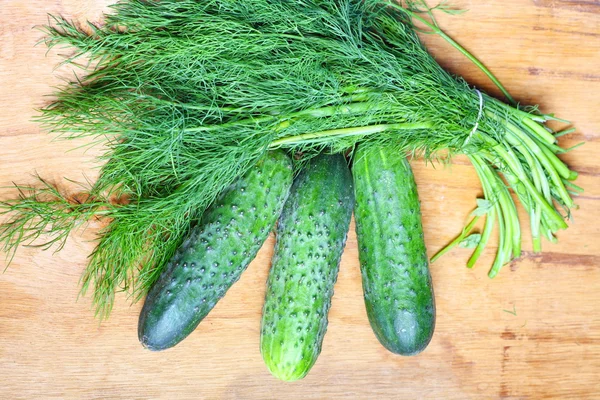 Manojo de eneldo fresco y pepinos en la mesa de madera — Foto de Stock