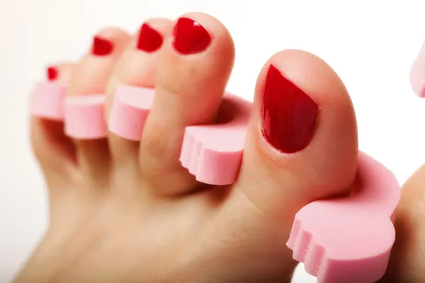 Pedicura del pie aplicando uñas rojas en blanco — Foto de Stock