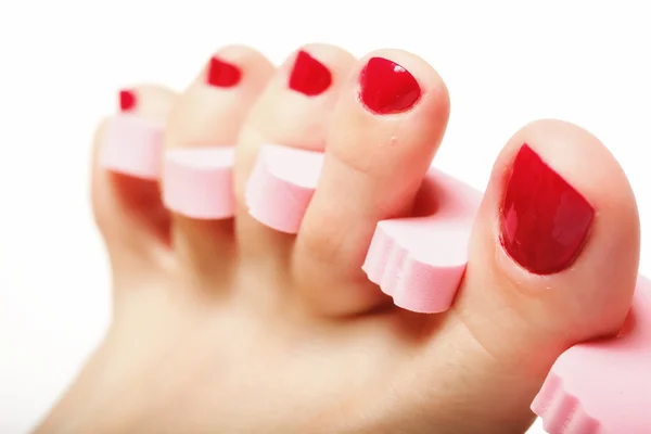 Pedicure pé aplicando unhas vermelhas sobre branco — Fotografia de Stock