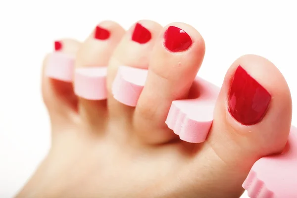 Pedicure del piede applicando unghie rosse su bianco — Foto Stock