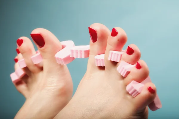 Voetpedicure aanbrengen van rode teennagels op blauw — Stockfoto