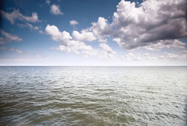 Bewölkter blauer Himmel über einer Meeresoberfläche — Stockfoto