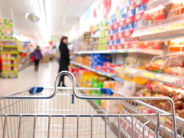 Frau im Supermarkt mit Einkaufswagen — Stockfoto