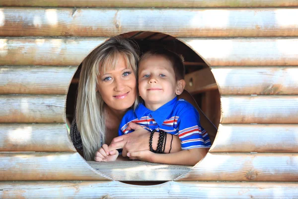 Mãe e filho espreitam através do buraco no playground — Fotografia de Stock