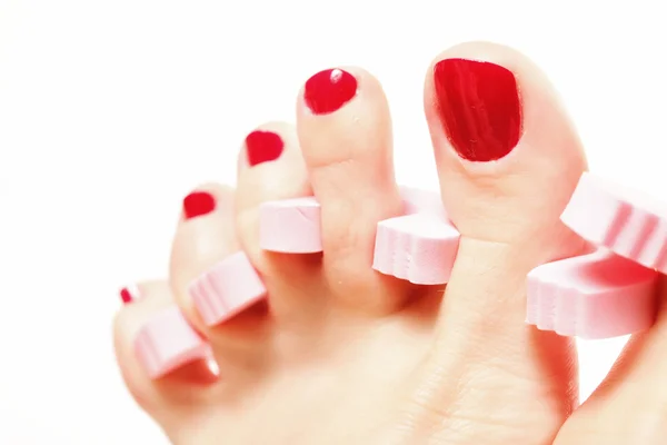 Pedicura del pie aplicando uñas rojas en blanco — Foto de Stock