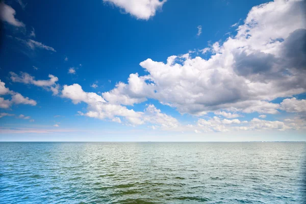 Cloudy blue sky above a surface of the sea — Stock Photo, Image