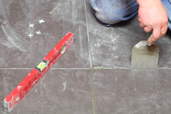 Construction worker is tiling at home tile floor adhesive — Stock Photo, Image