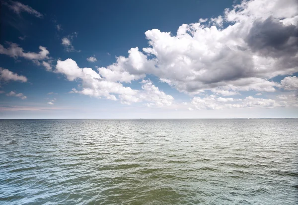 Cloudy blue sky above a surface of the sea — Stock Photo, Image