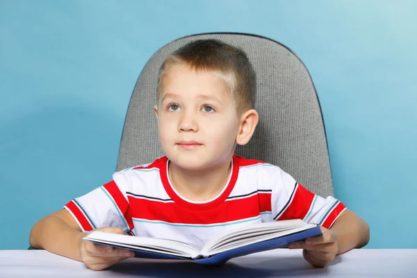 Criança menino criança lendo um livro sobre azul — Fotografia de Stock