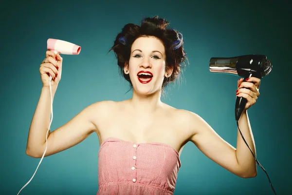 Funny girl in curlers with hairdryer styling hair — Stock Photo, Image