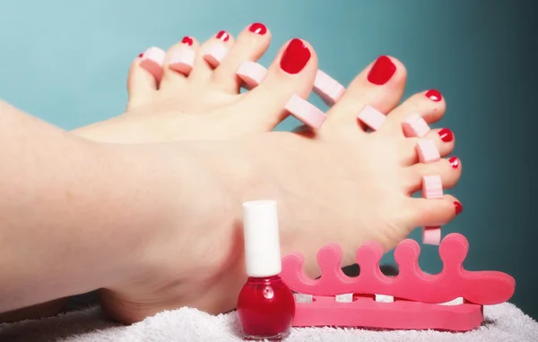 Fußpediküre mit roten Fußnägeln auf blauem Grund — Stockfoto