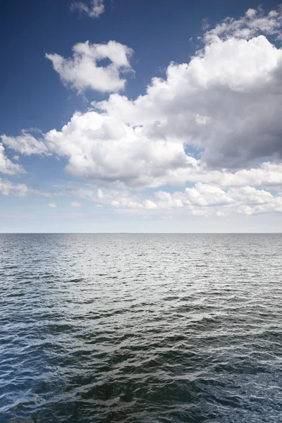 Cloudy blue sky above a surface of the sea Royalty Free Stock Images
