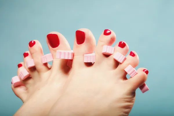 Voetpedicure aanbrengen van rode teennagels op blauw — Stockfoto