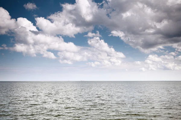 Bewölkter blauer Himmel über einer Meeresoberfläche — Stockfoto